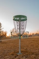 a green frisbee golf basket in a field