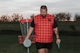 A man holding a frisbee standing next to a frisbee golf net