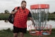A man standing next to a frisbee golf net