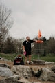 Man standing by disc golf basket with disc and bag