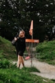 Man walking past a disc golf basket with a bag.