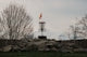 Disc golf basket with orange flag on rocky mound.