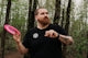 Man holding pink disc golf disc in forest
