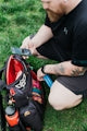 Man packing disc golf bag with phone and water bottle.