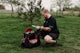Man with disc golf bag in grassy field.