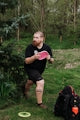 Man throwing a pink disc golf disc in a park.