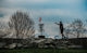 Man throwing disc golf disc towards basket on course